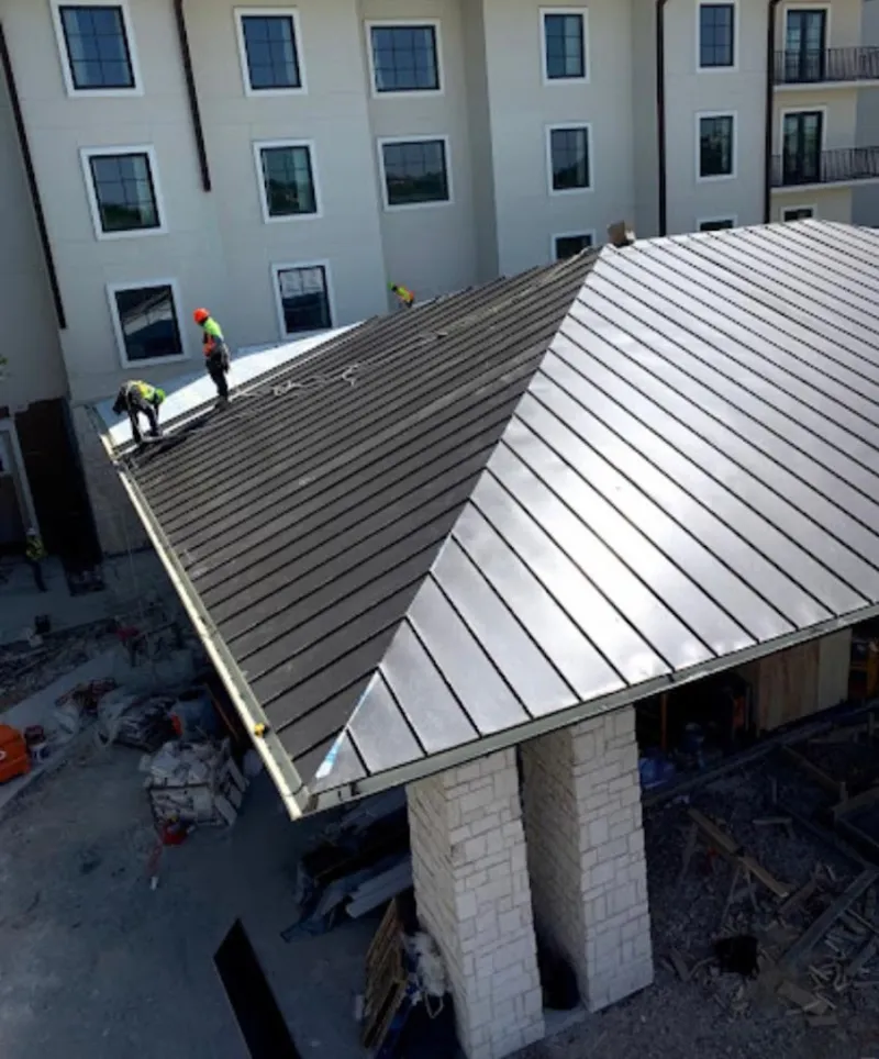 Crew installing standing seam metal roof panels on a commercial project in South Portland